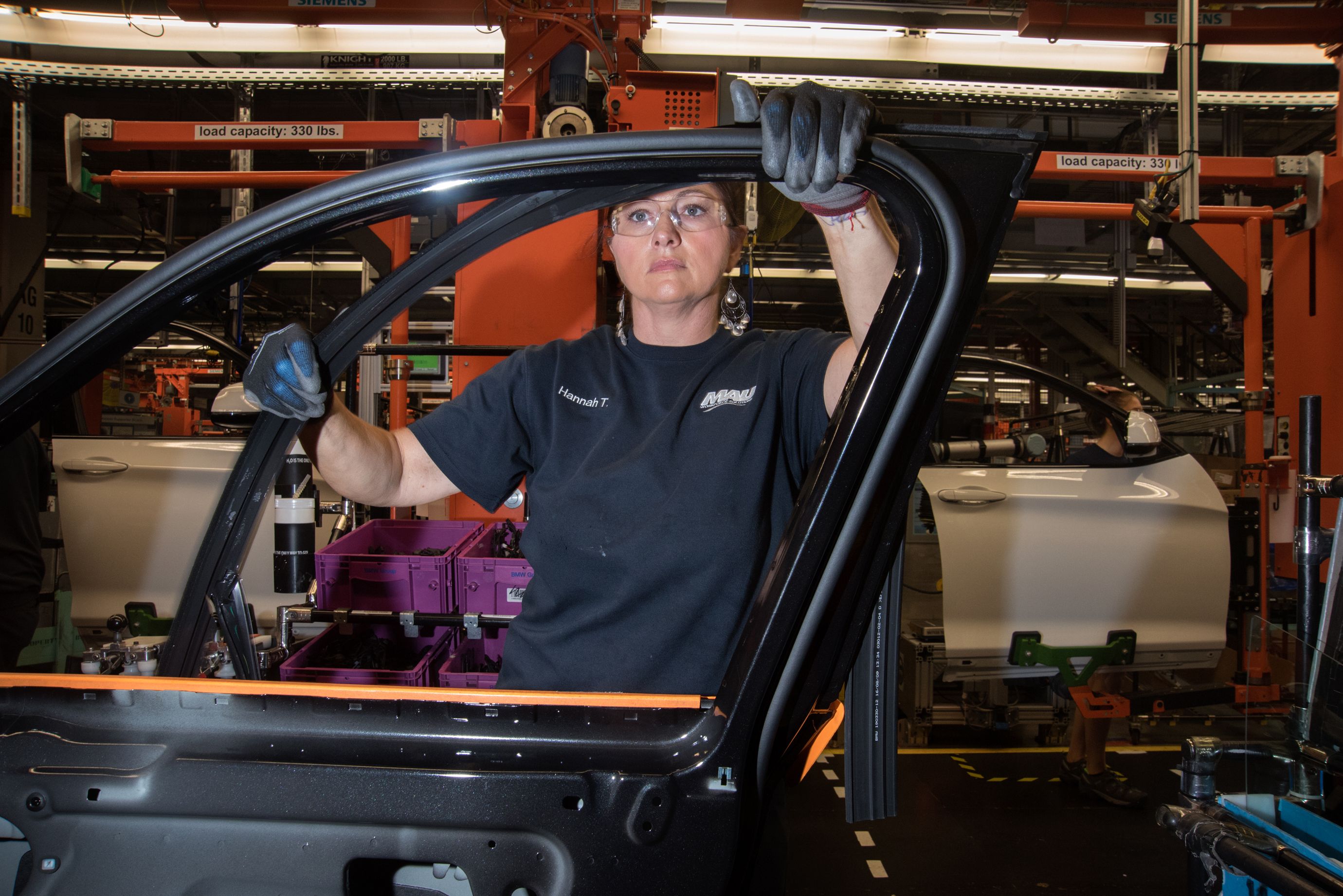 An employee of MAU, a firm that provides contract workers to BMW, helps to assemble a door. (5 of 7)