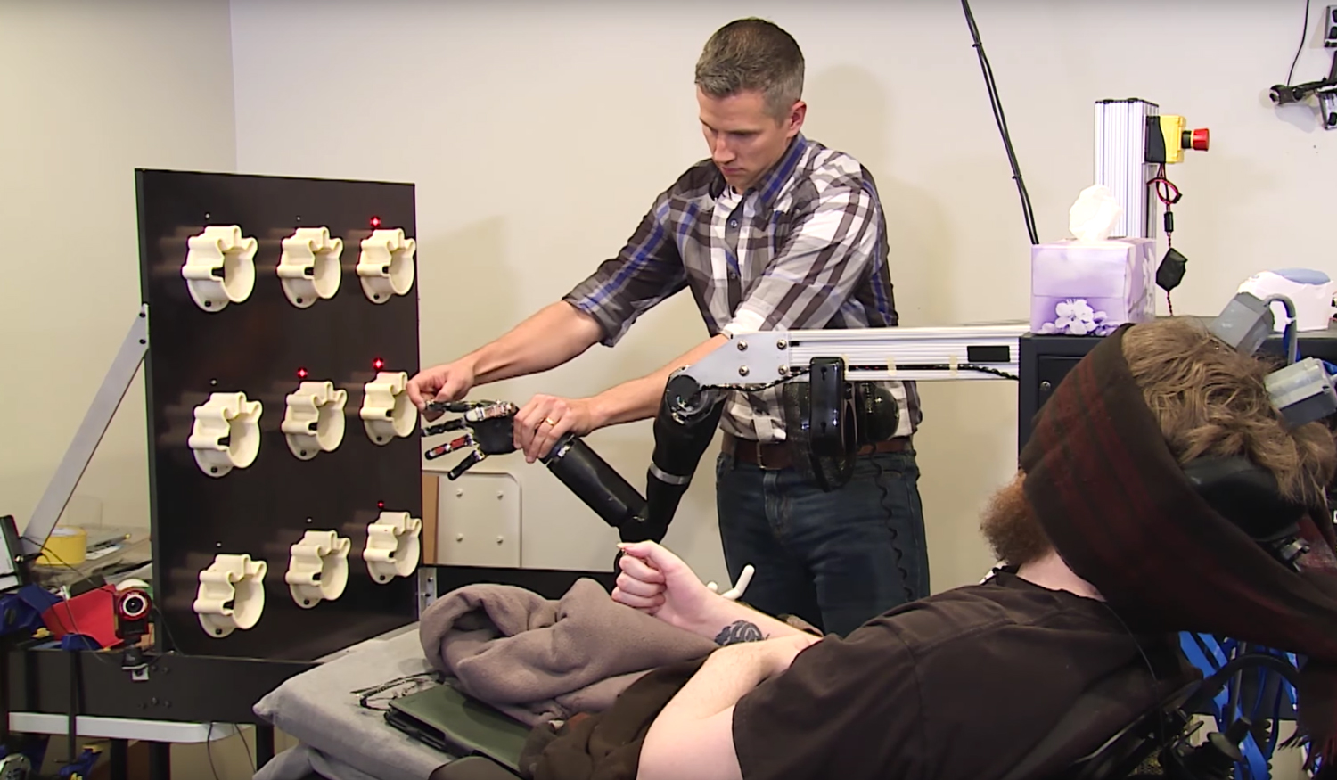 Nathan Copeland, seated, is tested on his sense of touch through a robotic arm.