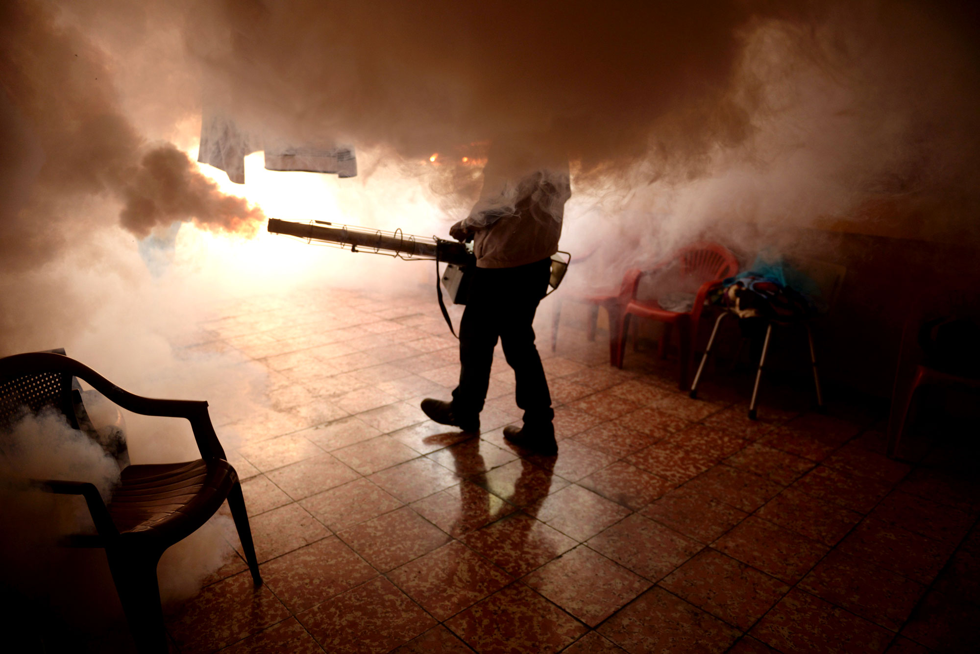 A health worker fumigates a home in El Salvador against mosquitoes to prevent the spread of the Zika virus.