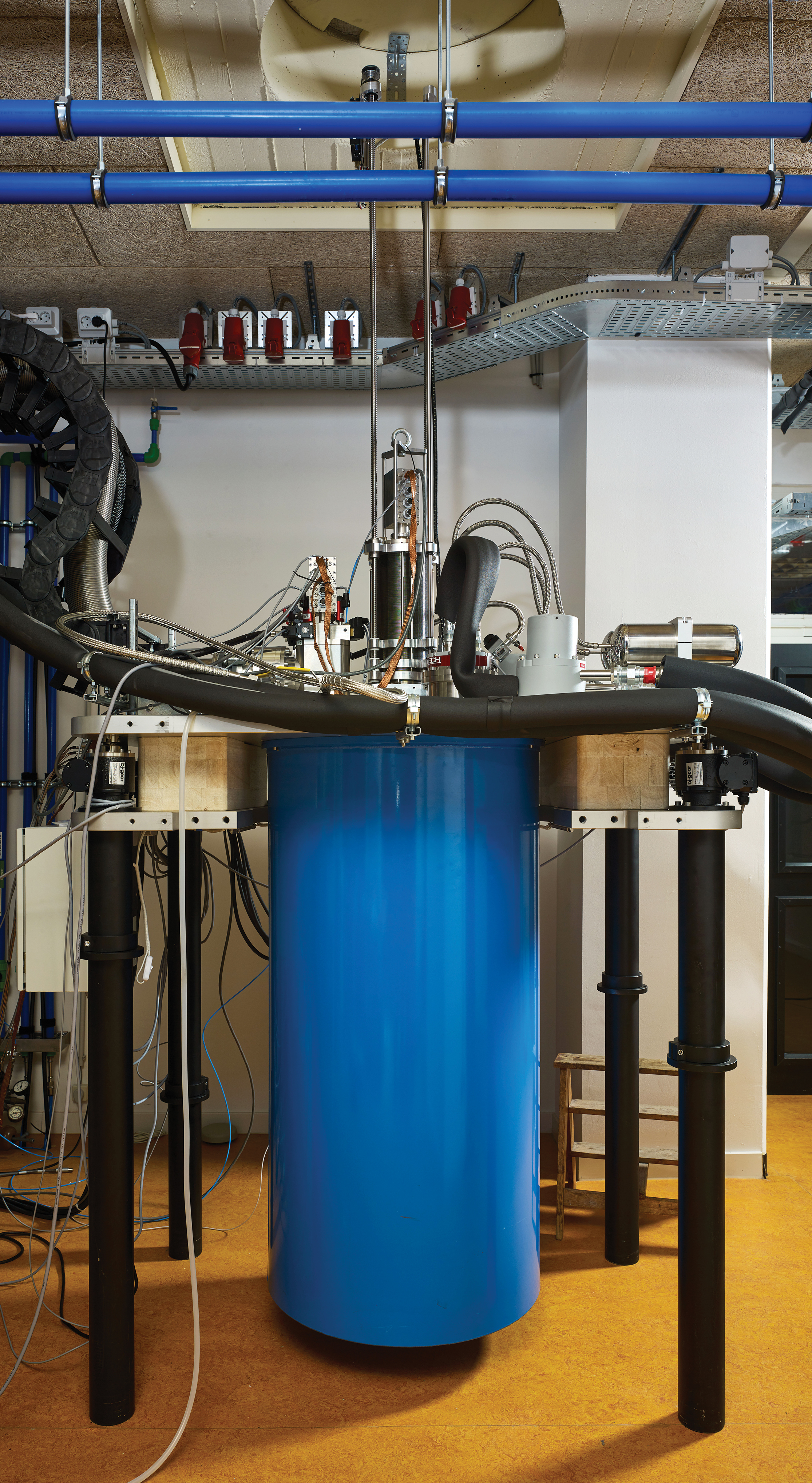 This blue refrigerator gets down to just above absolute zero, making quantum experiments possible on tiny chips deep inside it. On subsequent pages are scenes from the Delft lab where the experiments are prepared.