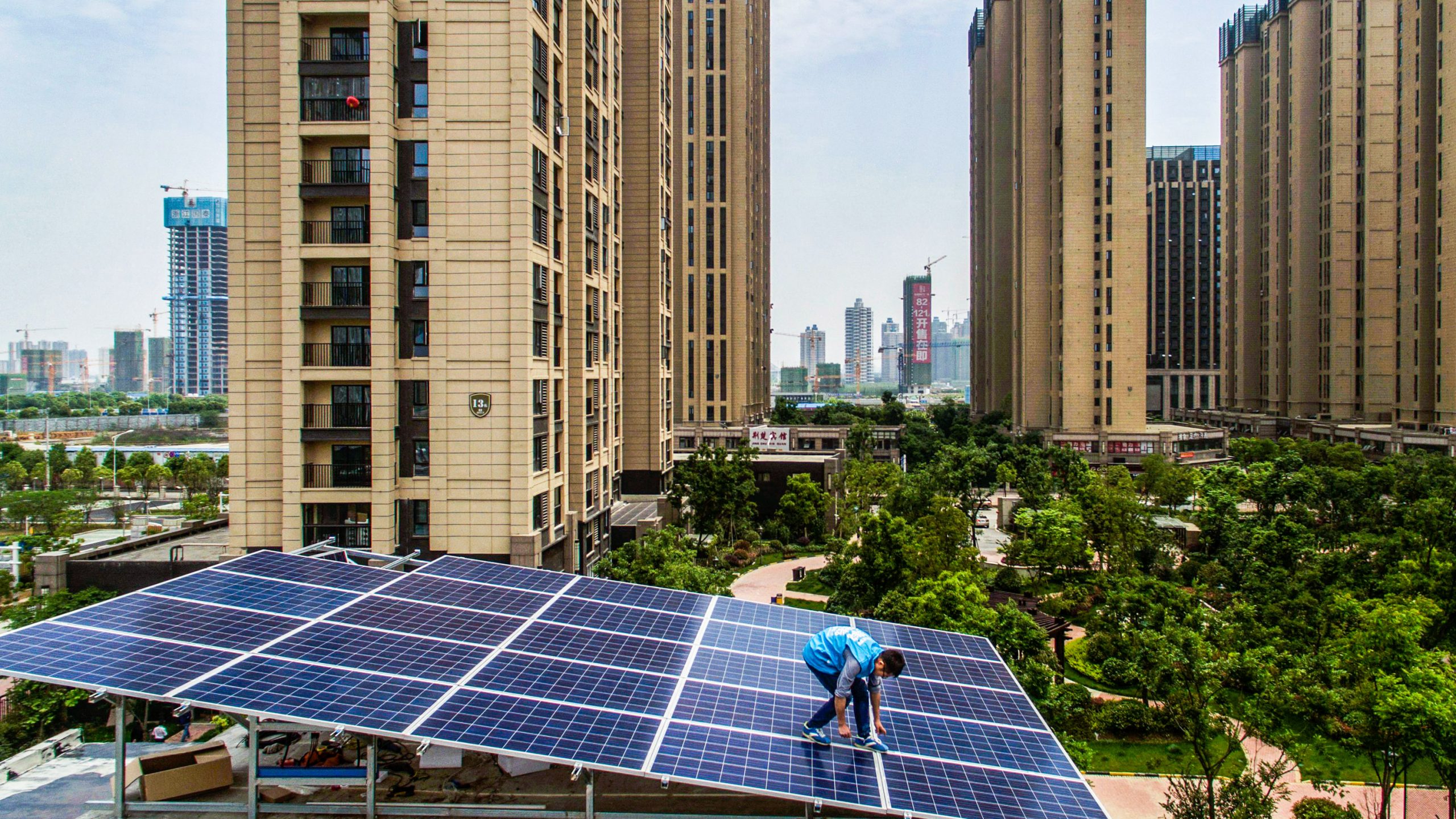 A worker from Wuhan Guangsheng Photovoltaic Company installs a solar panel project on the roof of a building