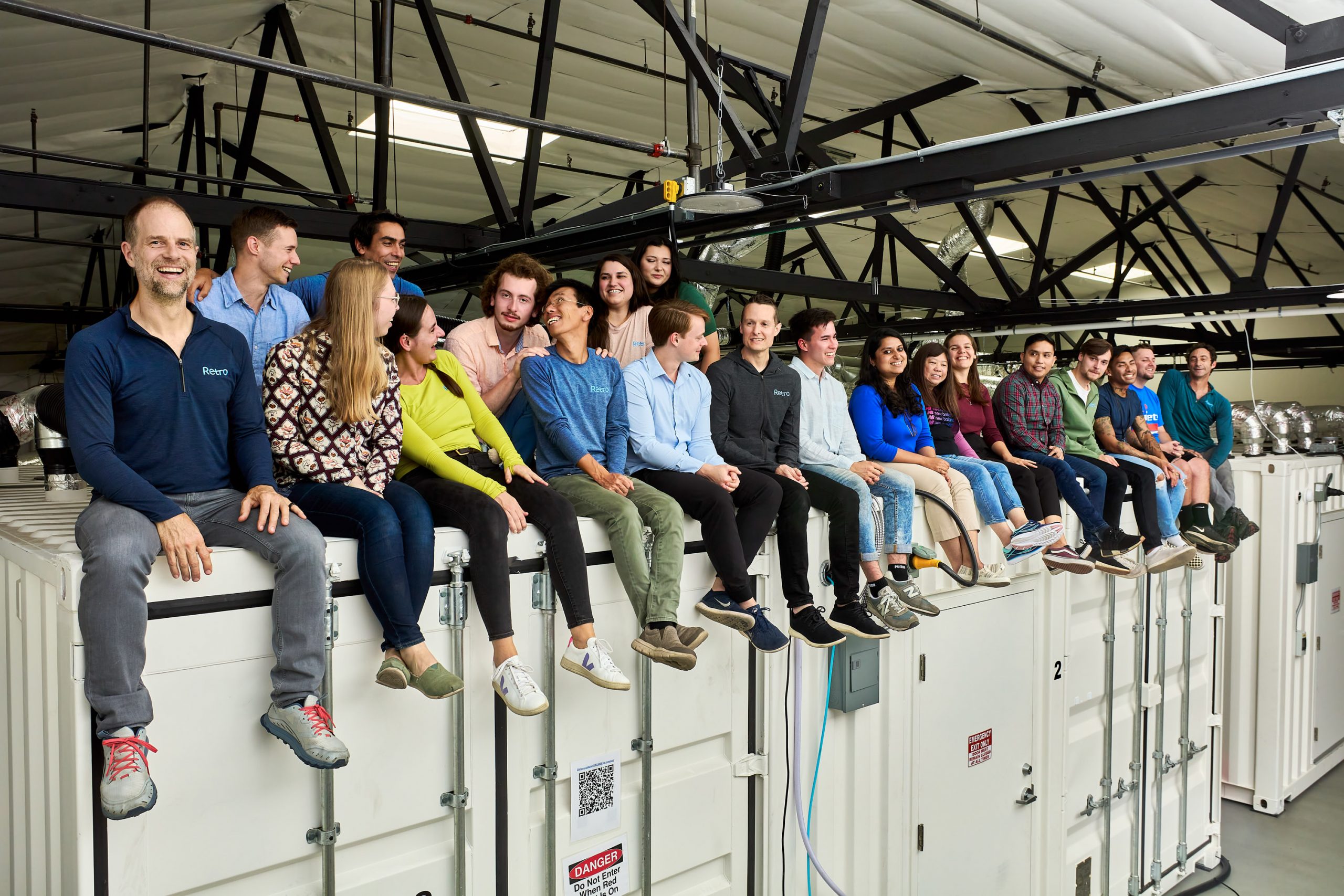 Retro Bio employees sitting on the top of the shipping containers that make up their lab space