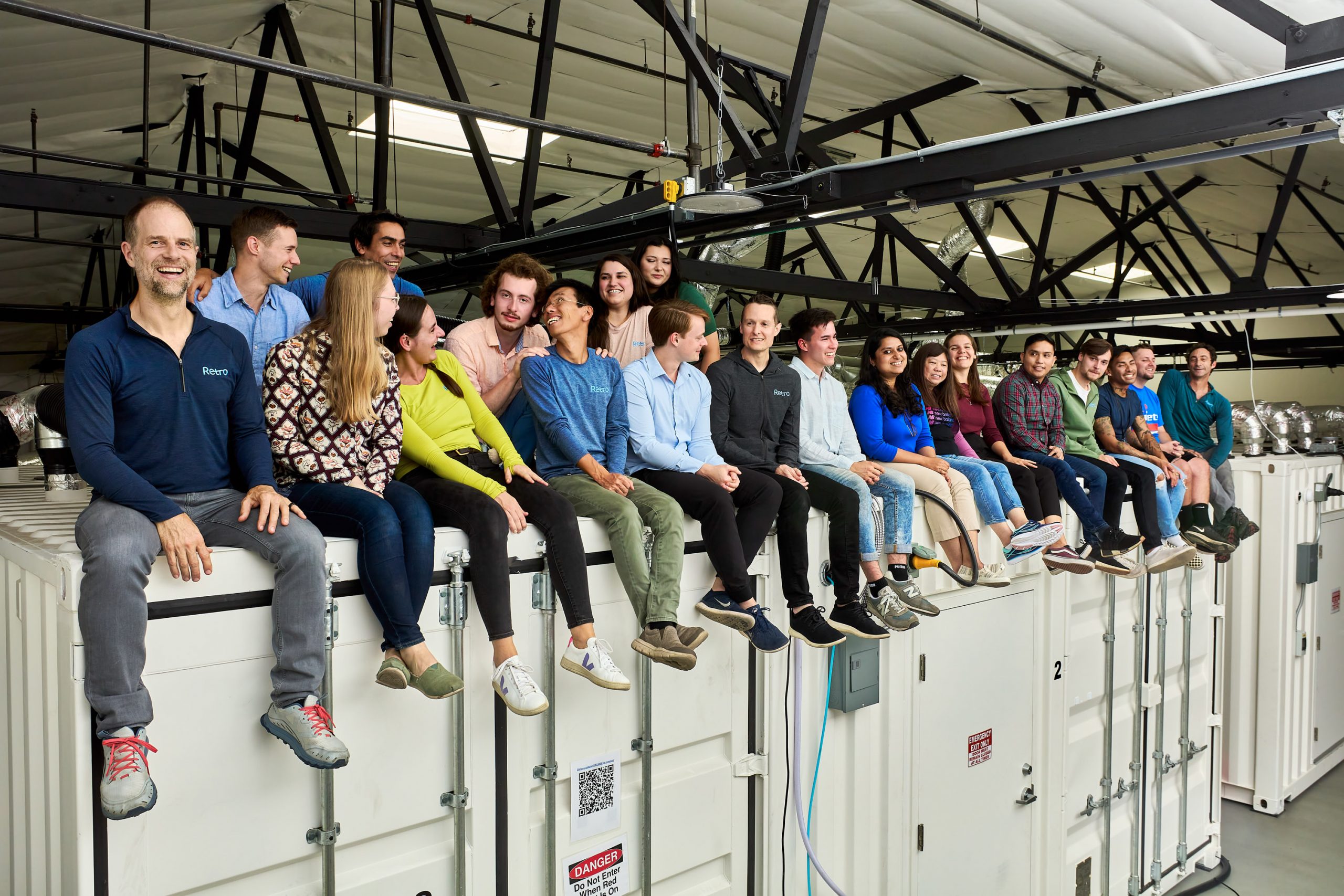 Retro Bio employees sitting on the top of the shipping containers that make up their lab space